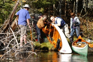 WCHA members help empty water from an overturned canoe.